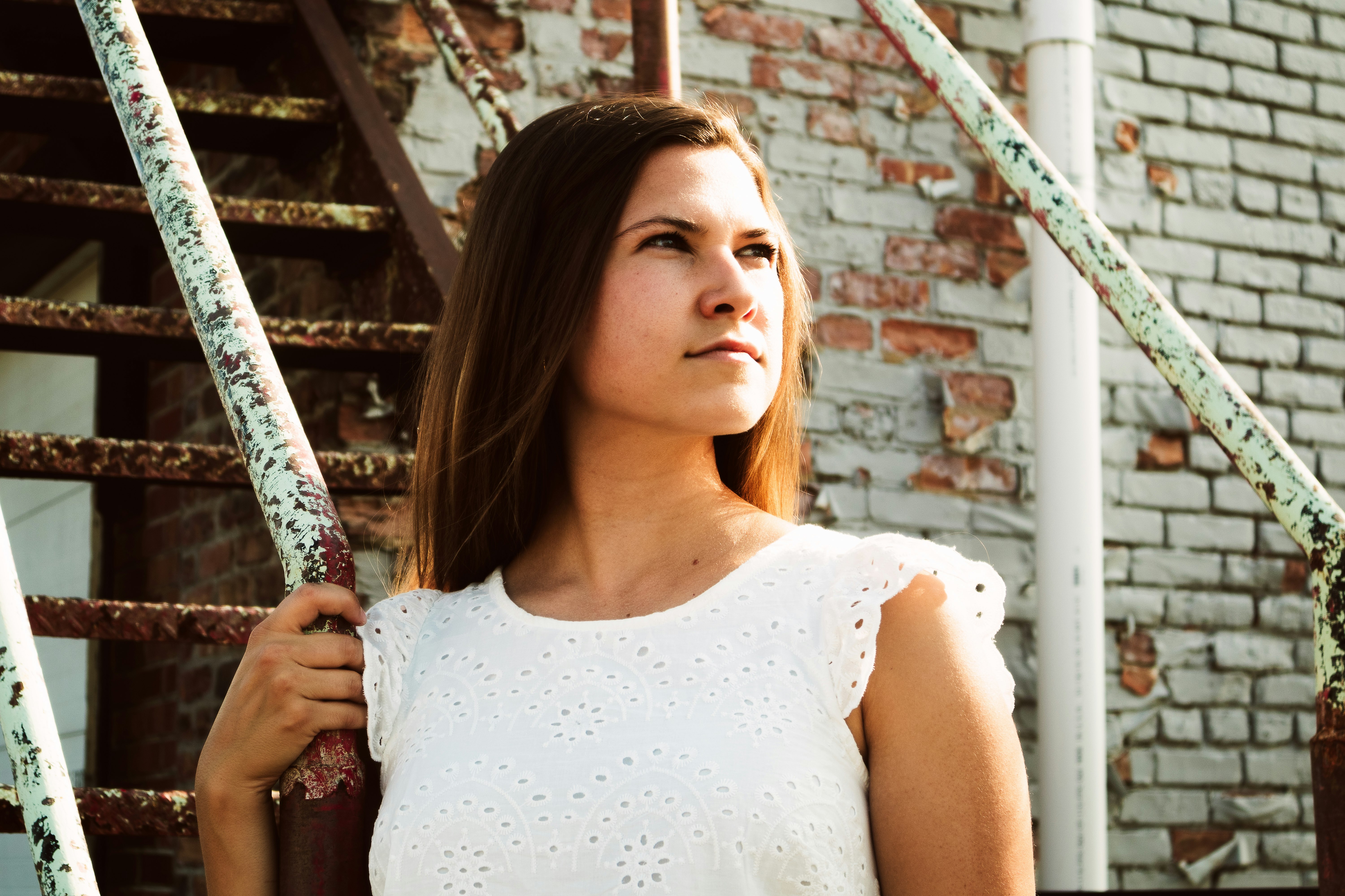 woman in white tank top holding on white metal bar during daytime